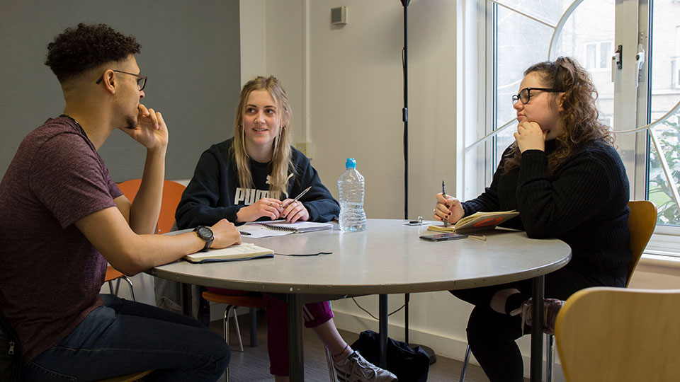 A group of students chatting in a communal area inside Loring Hall