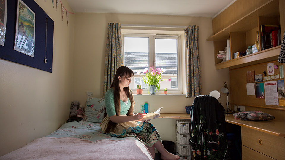 A student sitting on her bed in Loring Hall