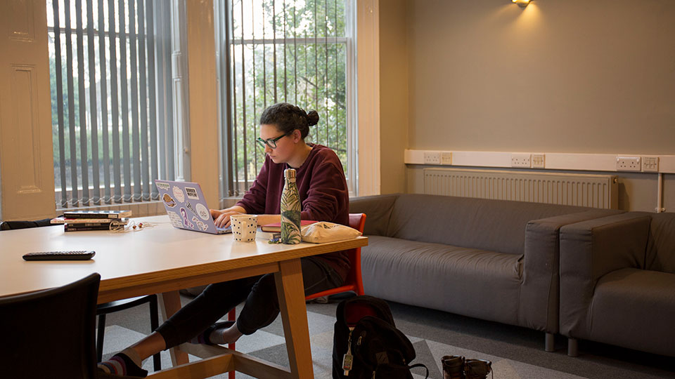 A female student sitting in a communal area in Raymont Hall